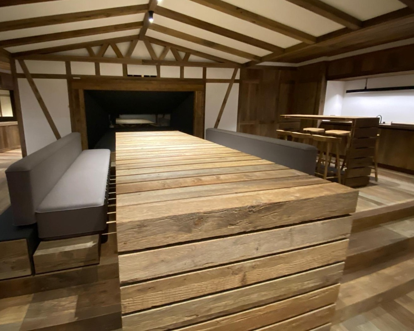 Finished hospitality interior using reclaimed oak cladding, counter surfaces, and exposed timber elements