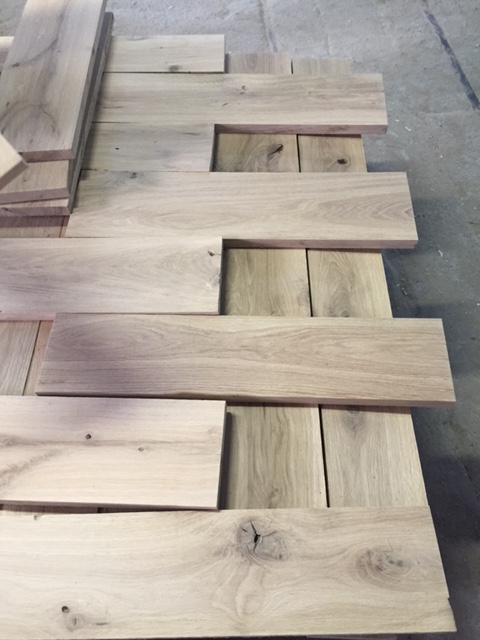 Prepared reclaimed oak planks with visible grain, knots, and natural character for project review