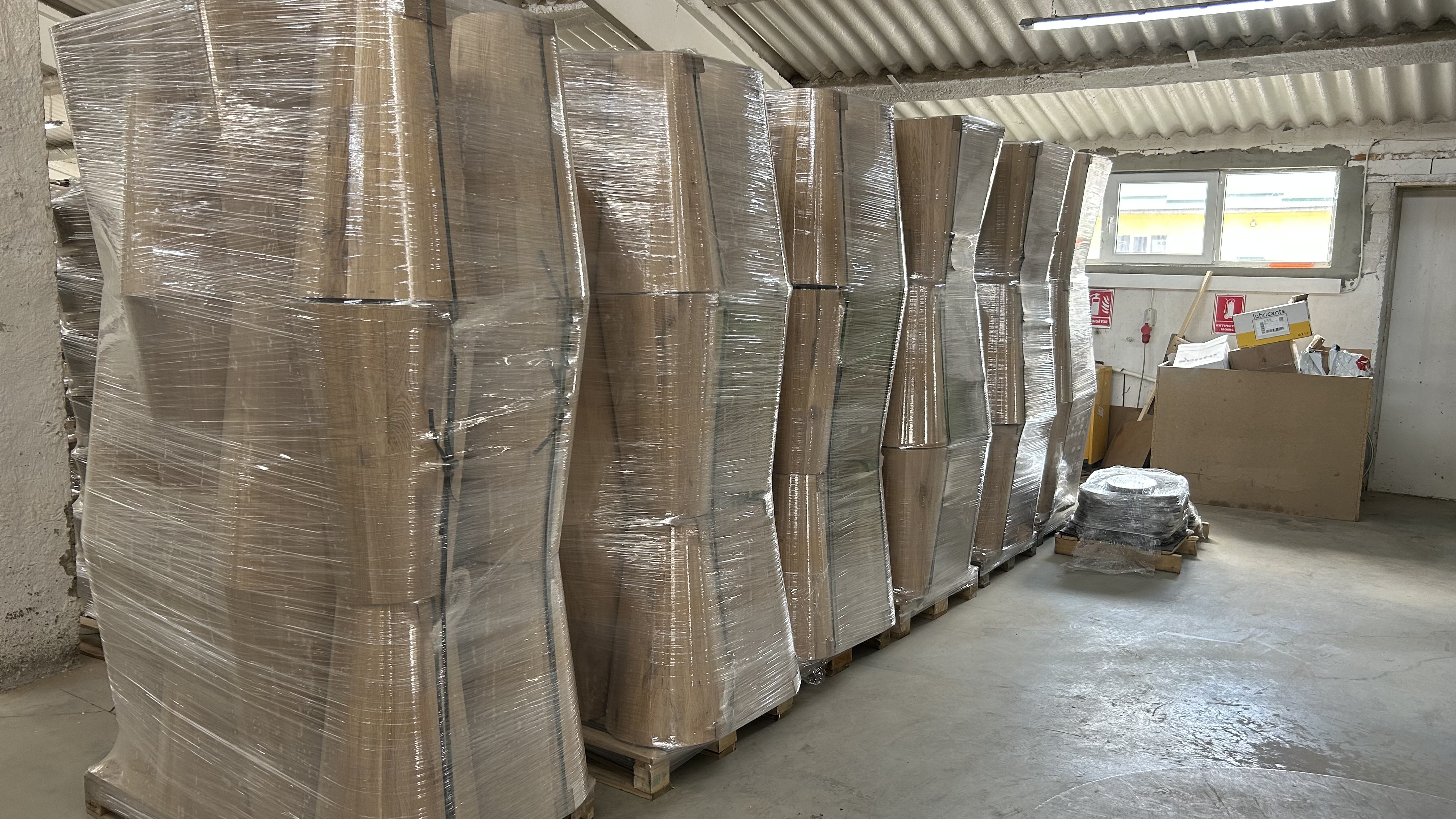 Finished solid wood furniture wrapped and packaged on pallets, ready for delivery